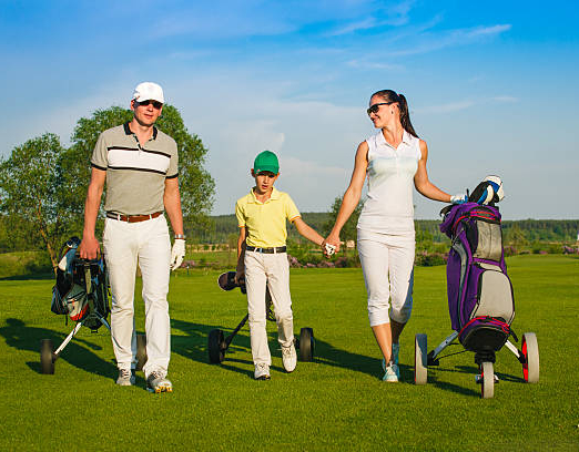 Family golfers walking on golf course at sunny day